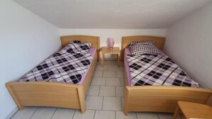A small, clean room with two wooden beds, a small table, and a tiled floor. - Erbacher Hof  (Homburg)