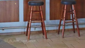 A bar area with wooden stools, hanging lights, and shelves stocked with bottles. - Erbacher Hof  (Homburg)