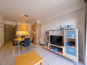 Cozy living space with a compact kitchen, dining area, and large flat-screen TV.