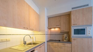 A modern kitchen with wooden cabinets, a stainless steel sink, a built-in dishwasher, and a microwave. - Apartment With 2 Bedrooms and sea View (Middelkerke)