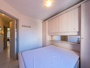 Quarto com cama, armários embutidos de madeira e iluminação no teto.