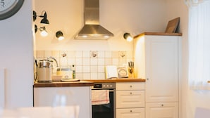 Uma cozinha compacta com armários brancos, um exaustor de aço inoxidável e painel de azulejos.