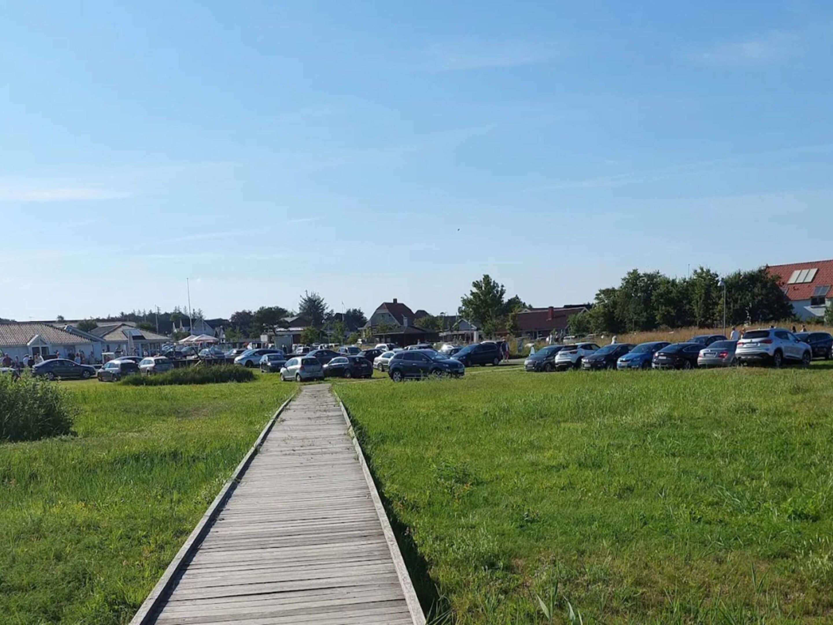 A parking lot with cars and a wooden walkway leading to a building.