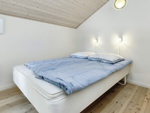 A single bed with a white mattress and a blue blanket, two wall-mounted light fixtures, and a wooden ceiling. - 4 Star Holiday Home in Hadsund (Hadsund)