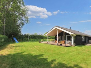 A house with a covered patio, a slide, and a lawn. - 4 Star Holiday Home in Hadsund (Hadsund)