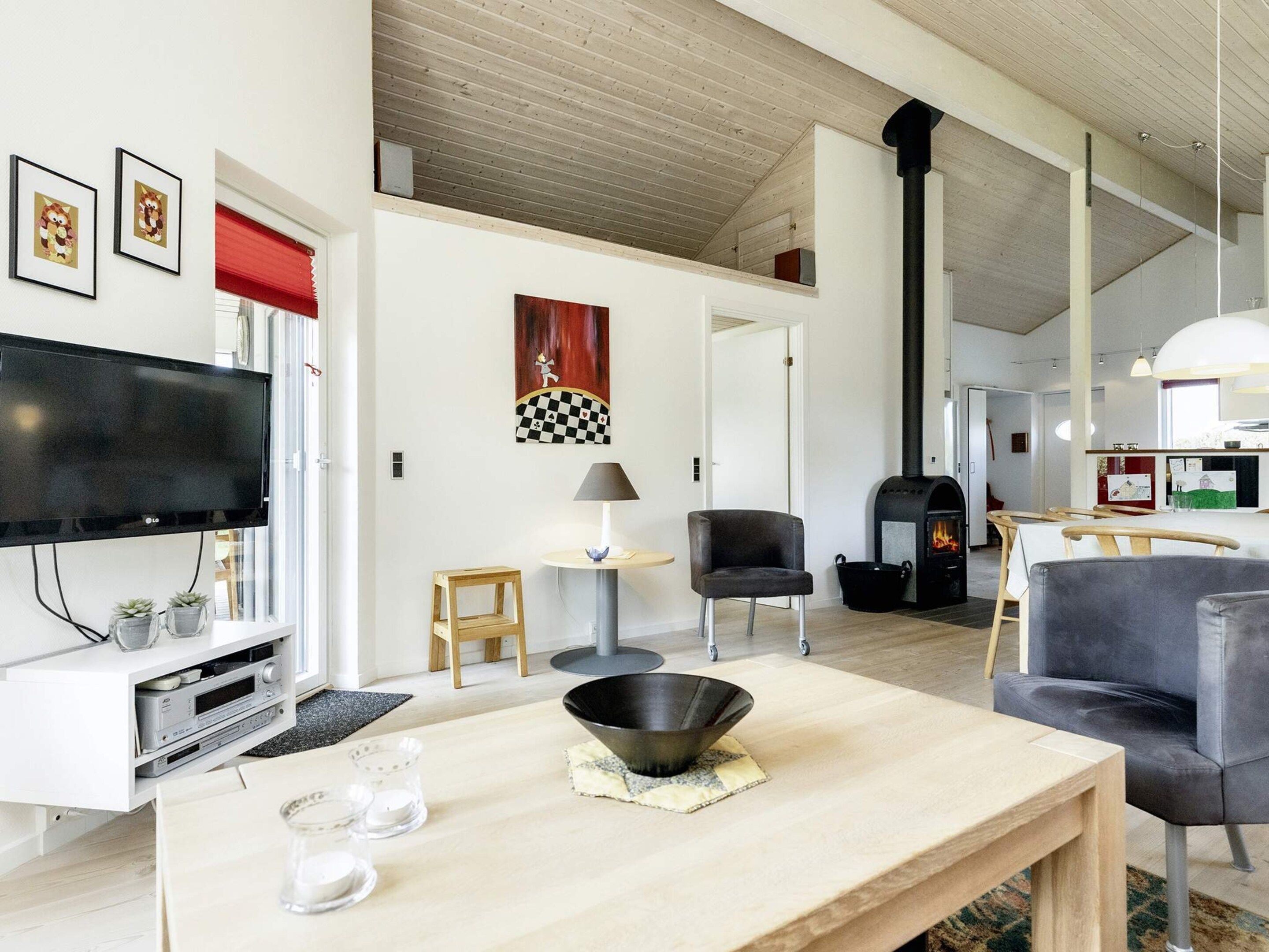 A modern living room with a flat-screen TV, a fireplace, and a dining area with a table and chairs.