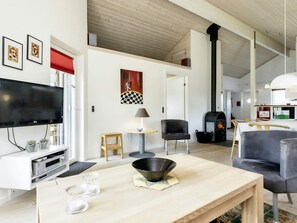 A modern living room with a flat-screen TV, a fireplace, and a dining area with a table and chairs. - 4 Star Holiday Home in Hadsund (Hadsund)