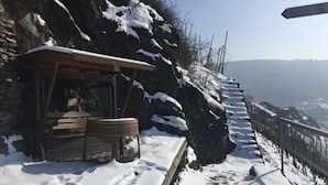 A rustic wooden cabin with a bench and a barrel, situated on a snow-covered slope with a view of the valley below. - Holiday Apartment Pia Stadfeld (Mehring)