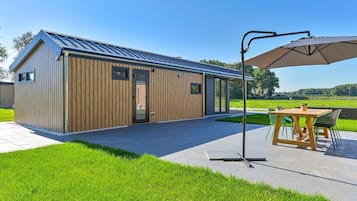 A modern building with a metal roof, a wooden door, and a covered patio area with a table and chairs.