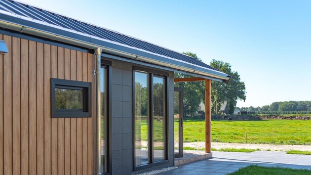 A modern building with a wooden facade, large glass doors, and a covered outdoor area. - Cozy Chalet With Unobstructed Views (Hoogersmilde)
