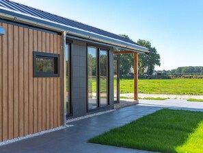 A modern building with a wooden facade, large glass doors, and a covered outdoor area. - Cozy Chalet With Unobstructed Views (Hoogersmilde)