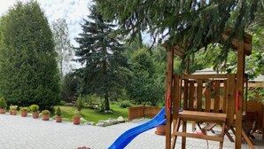 A wooden play structure with a blue slide and a wooden bench. - Yellow House Modern Retreat (Cesky Jiretin)