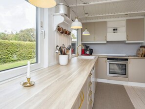 A modern kitchen with a large window, stainless steel appliances, and a minimalist design. - 6 Person Holiday Home in Tarm (Tarm)