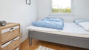 A bedroom with a bed, a window, a bedside table, and a wall-mounted picture.