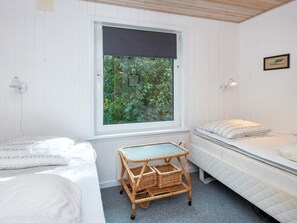 Alojamiento pequeño de una sola habitación, con dos camas, una ventana con vistas a zonas verdes y una mesita.