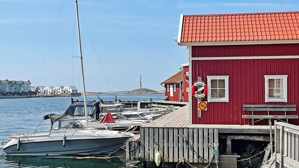 A red building with a tiled roof, docked boats, and a clear sky. - 4 Person Holiday Home in Bleket-by Traum (Bleket)