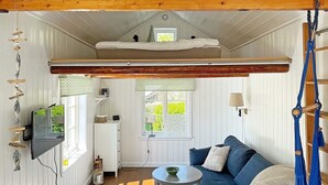 A loft-style bedroom with a bunk bed, a television, a dining table, and a blue sofa. - 4 Person Holiday Home in Bleket-by Traum (Bleket)