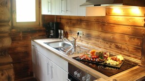 Una cocina compacta con paredes de madera, un lavamanos integrado y una encimera con una tabla de fiambres.