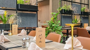 Un restaurant avec des tables et des chaises en bois, ainsi que des plantes en pot.
