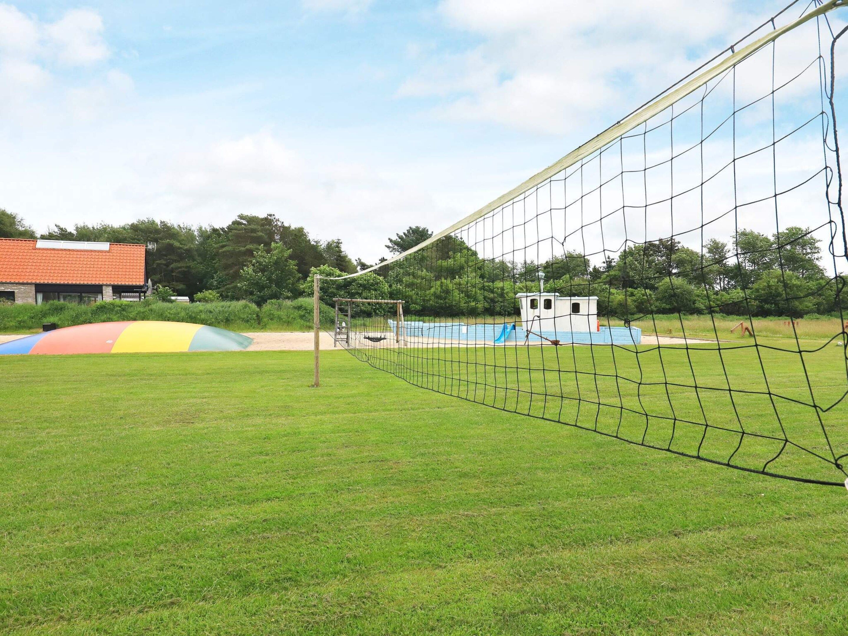 Een sportveld met een doelnet, een klein gebouw en een kleurrijke glijbaanconstructie.
