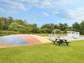 Un parque infantil con un tobogán colorido, columpios y una mesa de picnic.