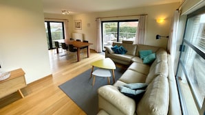 A spacious living area with a wooden dining table, a beige sofa, and a small white table. - Villa in Oostduinkerke Near Dunes (Koksijde)