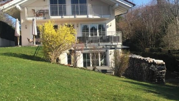 Ein zweistöckiges Haus mit Balkon, Steinmauer und gepflegtem Rasen.