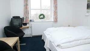 A hotel room with a single bed, a desk with a chair, a television, and a window with curtains. - 4 Person Holiday Park Home in Hanstholm (Hanstholm)