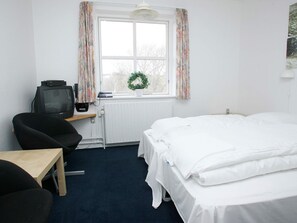 A hotel room with a single bed, a desk with a chair, a television, and a window with curtains. - 4 Person Holiday Park Home in Hanstholm (Hanstholm)