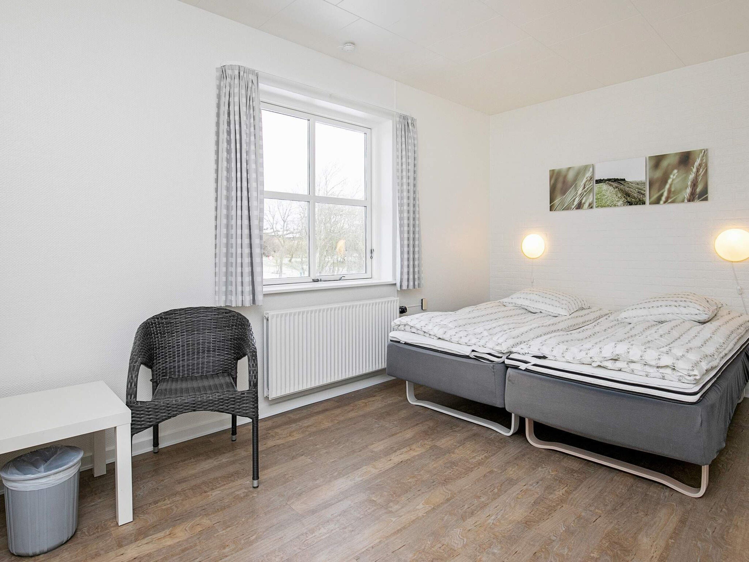 Et soveværelse med seng, stol, bord og radiator.