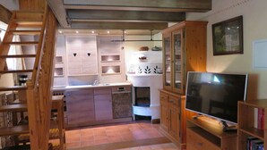 A compact kitchen with a central island, wooden cabinets, and a built-in TV. - Nagelsmederij in het Huis Waldwinkel (Aschau im Chiemgau)