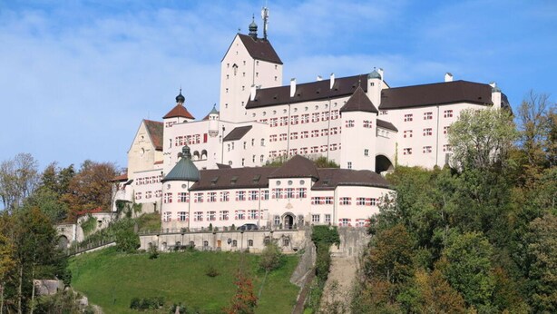 A large, historic building with multiple towers and a central courtyard, surrounded by lush greenery. - Nagelsmederij in het Huis Waldwinkel (Aschau im Chiemgau)