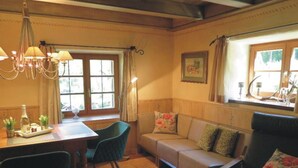 A cozy room with a dining table, chairs, a sofa, and a window with curtains. - Nagelsmederij in het Huis Waldwinkel (Aschau im Chiemgau)