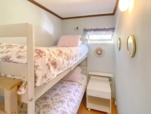 Une chambre avec un lit superposé, une fenêtre, une petite table et des décorations murales.