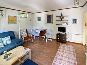A living room with a sofa, a dining table with chairs, a TV, and a fireplace. - 4 Person Holiday Home in Hollviken (Hollviken)