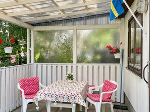 A covered patio with a table and chairs, a flag, and potted plants. - 4 Person Holiday Home in Hollviken (Hollviken)