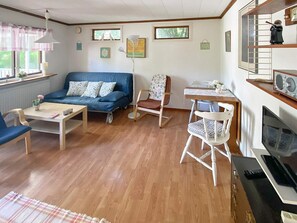 A cozy living room with a blue sofa, a wooden coffee table, a rocking chair, and a television. - 4 Person Holiday Home in Hollviken (Hollviken)
