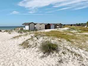 Una hilera de cabañas de playa frente a una arena y dunas.