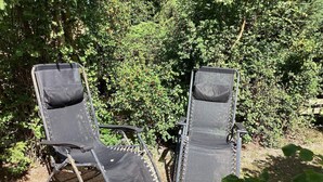 Two outdoor lounge chairs with metal frames and canvas seats, positioned on a grassy area with dense foliage in the background. - 4 Person Holiday Home in Hollviken (Hollviken)