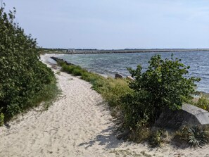 A sandy pathway alongside a body of water with vegetation on one side. - 4 Person Holiday Home in Hollviken (Hollviken)