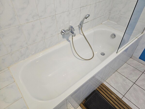 Un baño moderno con una bañera blanca, accesorios de cromo y una cabina de ducha de vidrio.