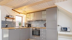 A modern kitchen with grey cabinets, a built-in oven, and a microwave on a white countertop. - 6 Person Holiday Home in Rodby (Rodby)