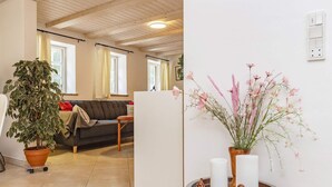 A living room with a sofa, a coffee table with decorative items, a potted plant, and a view of the outside through a window. - 6 Person Holiday Home in Rodby (Rodby)
