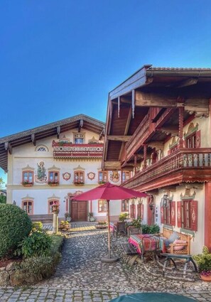 Il s’agit d’un bâtiment traditionnel doté d’un balcon, d’un escalier et d’un chemin pavé menant à un espace aménagé avec une table et des chaises.