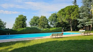 Piscina con dos bancos y una zona de césped.