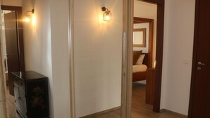 Un pasillo con suelo de madera, un armario de madera oscura y una cama al fondo.