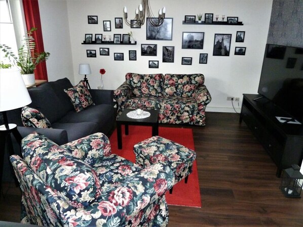 Ein Wohnzimmer mit einer Sofagarnitur, einem Couchtisch und einer TV-Konsole.