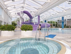 An indoor swimming pool with a slide and a water feature.