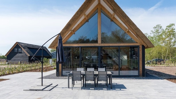 A modern building with a large glass facade and a thatched roof. - Chic Thatched-roof Stay (Baarle-Nassau)