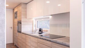 A modern kitchen with wooden cabinets, stainless steel appliances, and a window providing natural light. - Chalet in Kotschach Near Ski Area Vorhegg (Kotschach-Mauthen)